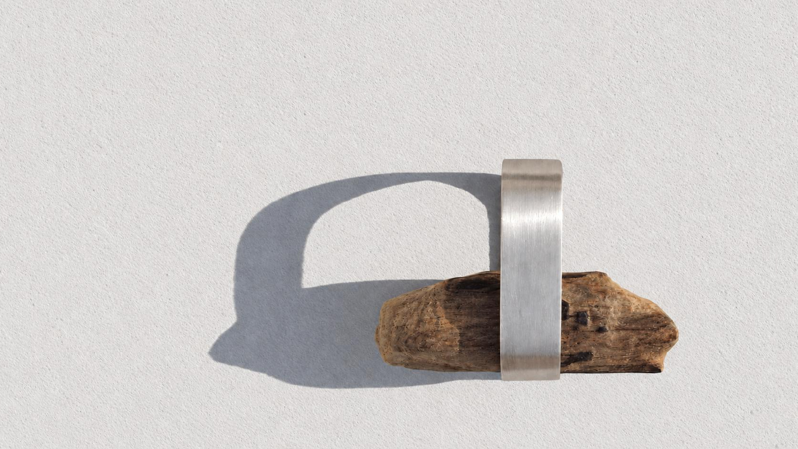 Silver ring holding a piece of wood and casting a geometric shadow